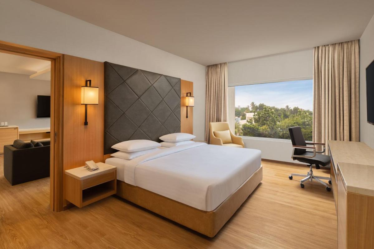 a hotel room with a large bed and a desk at Courtyard by Marriott Tiruchirappalli in Tiruchchirāppalli