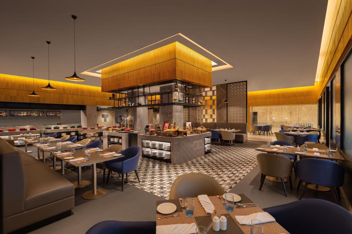 a restaurant with tables and chairs and a bar at Courtyard by Marriott Tiruchirappalli in Tiruchchirāppalli