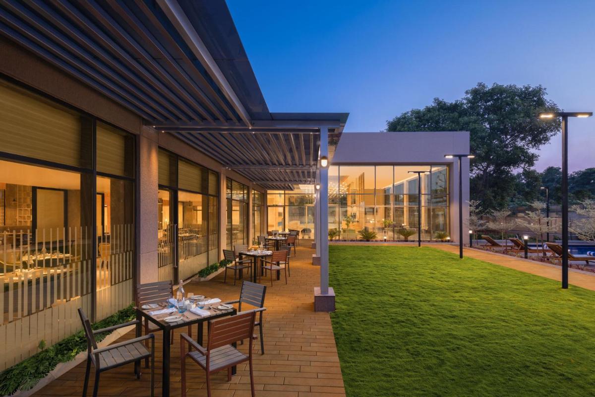 a patio with tables and chairs on a building at Courtyard by Marriott Tiruchirappalli in Tiruchchirāppalli