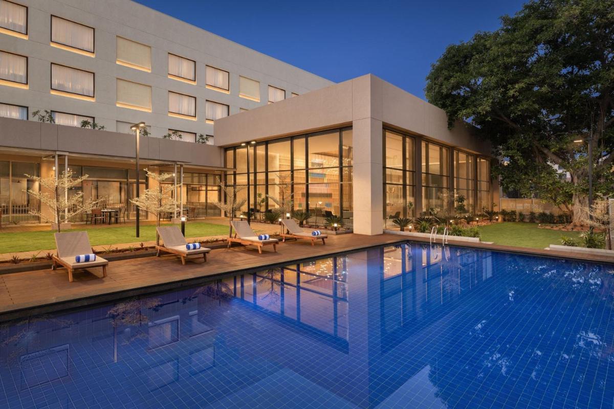 a hotel with a swimming pool in front of a building at Courtyard by Marriott Tiruchirappalli in Tiruchchirāppalli