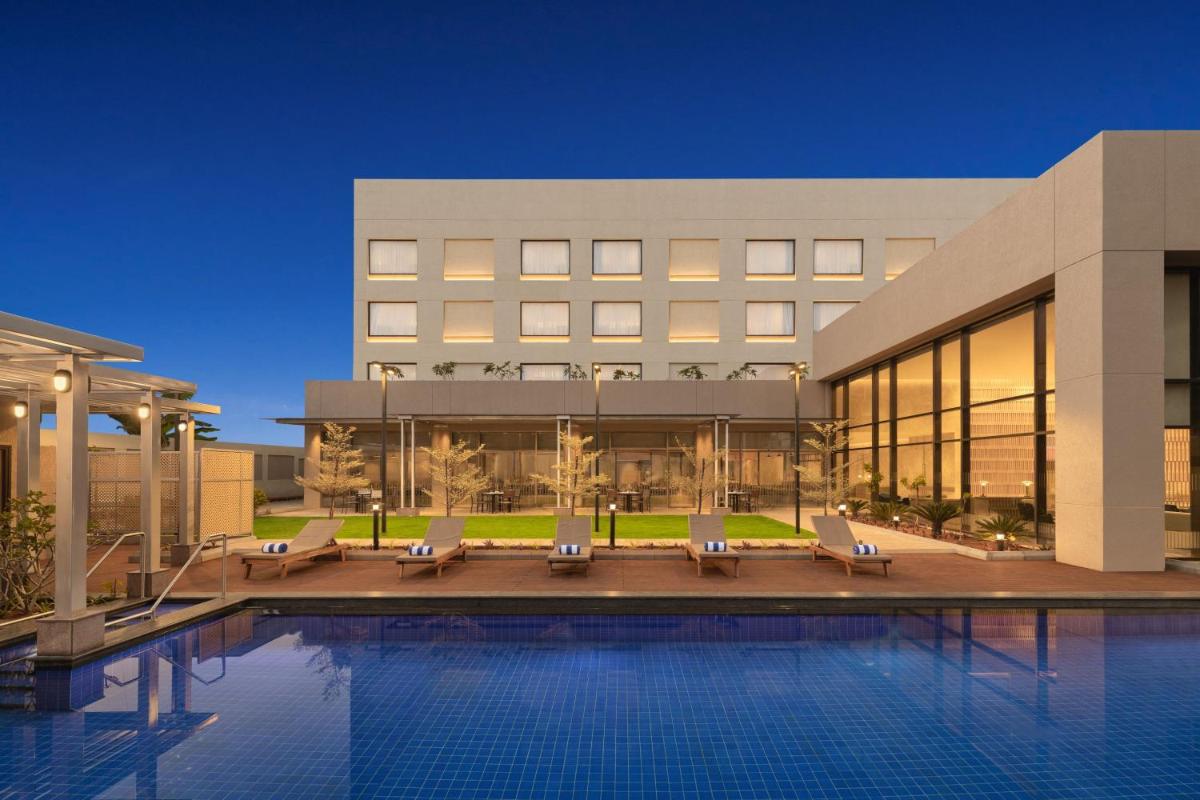 a hotel with a swimming pool in front of a building at Courtyard by Marriott Tiruchirappalli in Tiruchchirāppalli