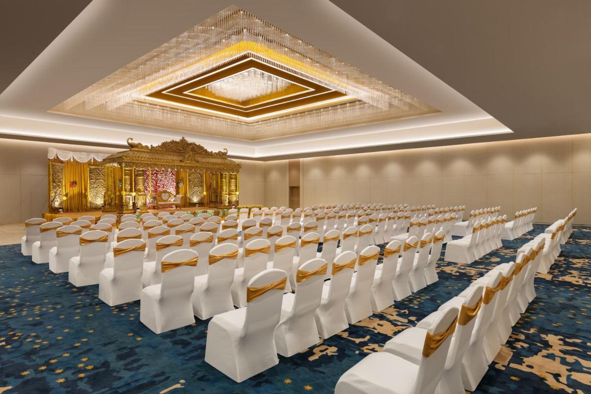 an empty banquet hall with white chairs and a ceiling at Courtyard by Marriott Tiruchirappalli in Tiruchchirāppalli