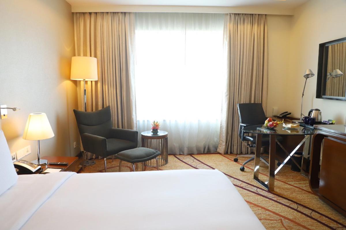 a hotel room with a bed and a desk and a window at DoubleTree by Hilton Gurgaon New Delhi NCR in Gurgaon