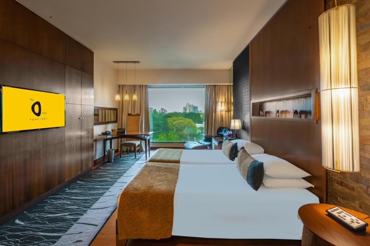 a hotel room with a large bed and a living room at O Hotel Pune in Pune