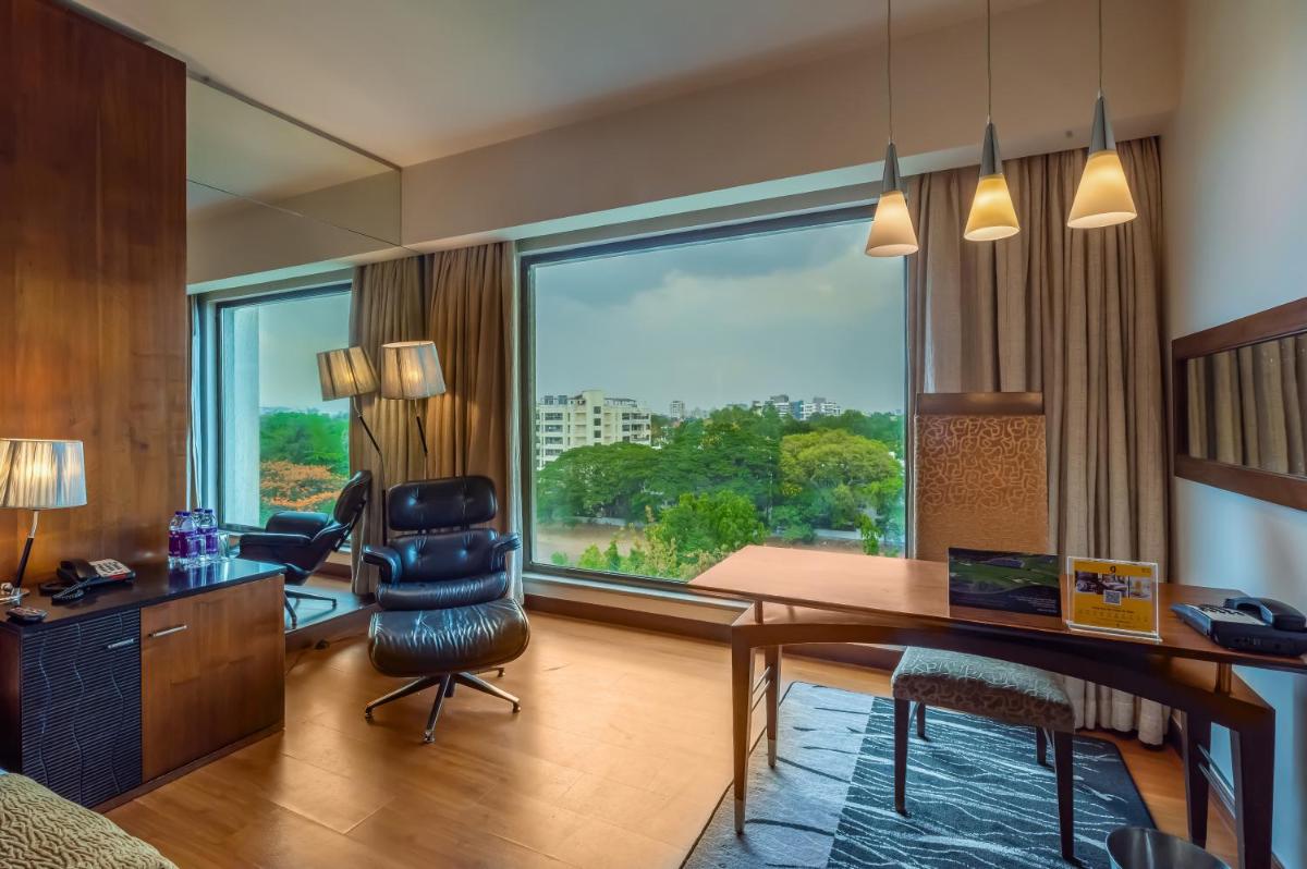 a room with a desk and a chair and a large window at O Hotel Pune in Pune