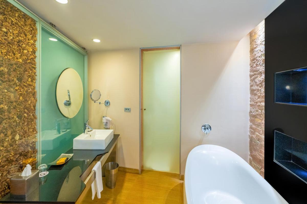 a bathroom with a tub and a sink and a mirror at O Hotel Pune in Pune