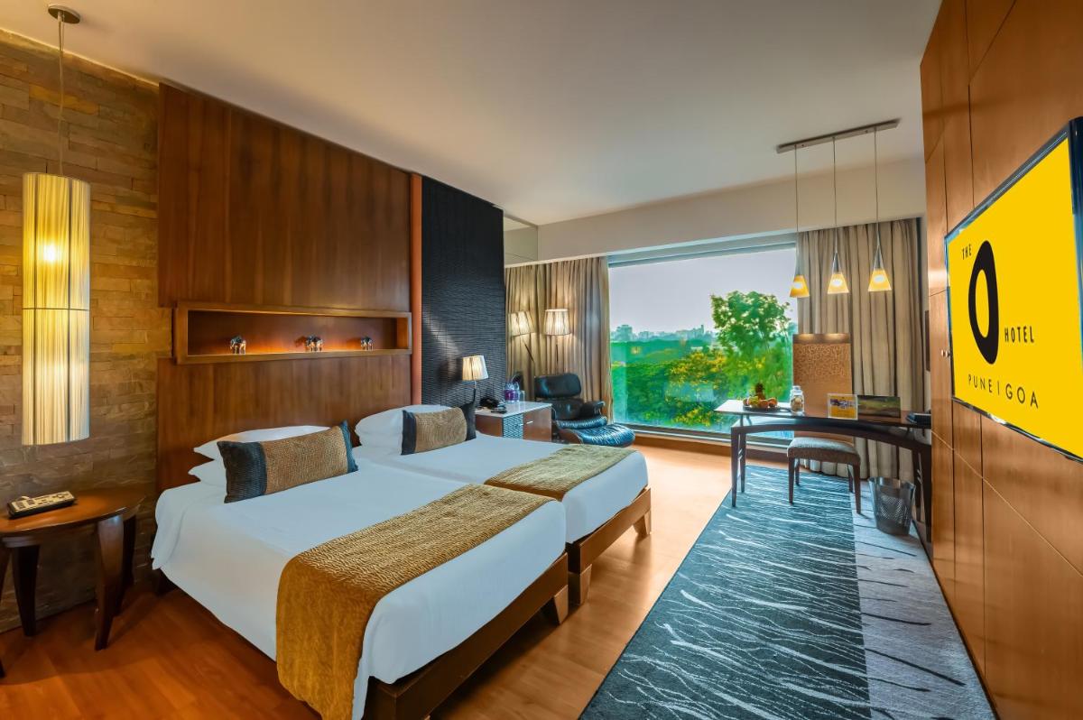 a hotel room with two beds and a large window at O Hotel Pune in Pune