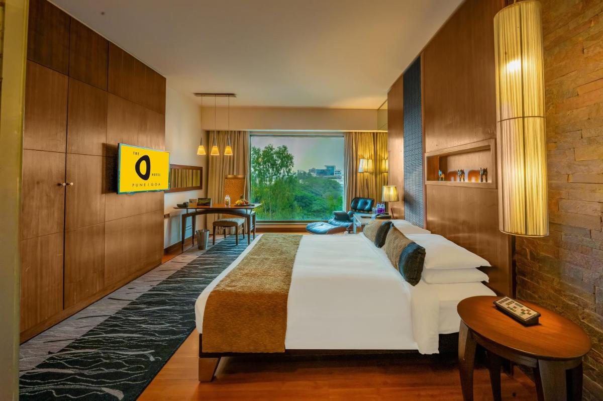 a hotel room with a large bed and a table at O Hotel Pune in Pune