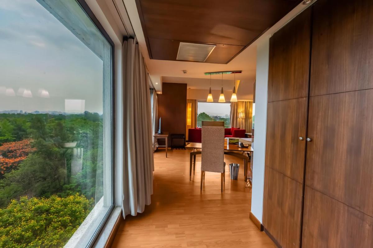 a living room with a dining room table and a large window at O Hotel Pune in Pune