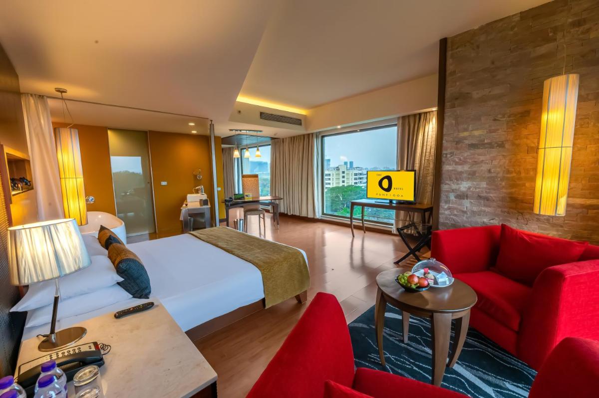 a hotel room with a bed and a red couch at O Hotel Pune in Pune