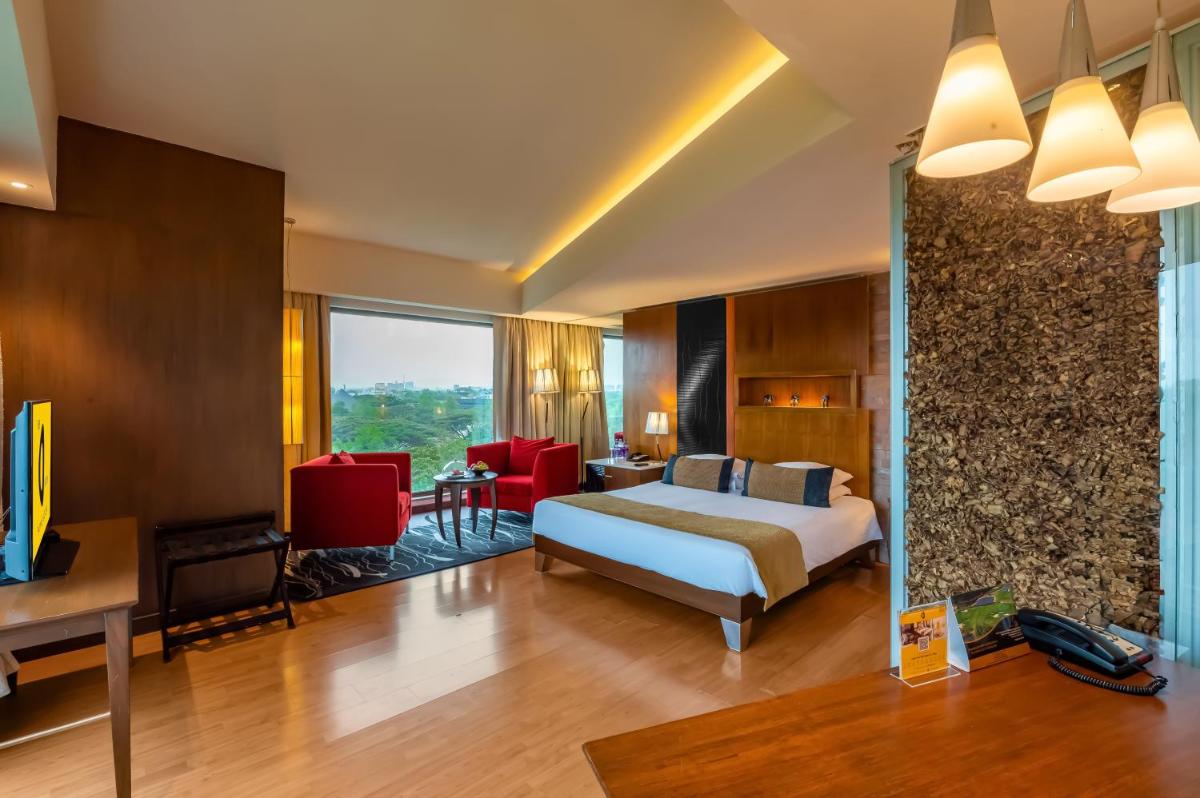 a hotel room with a bed and a table and chairs at O Hotel Pune in Pune