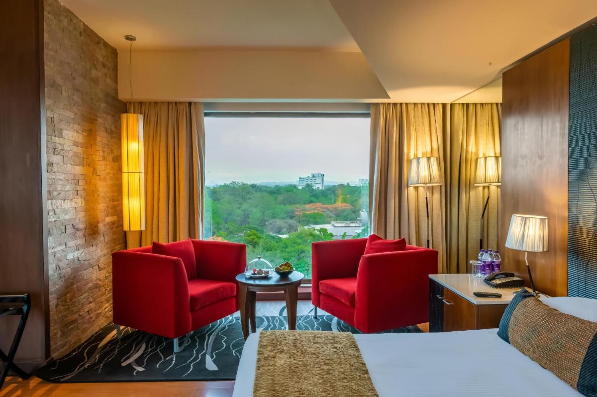 a hotel room with two red chairs and a window at O Hotel Pune in Pune