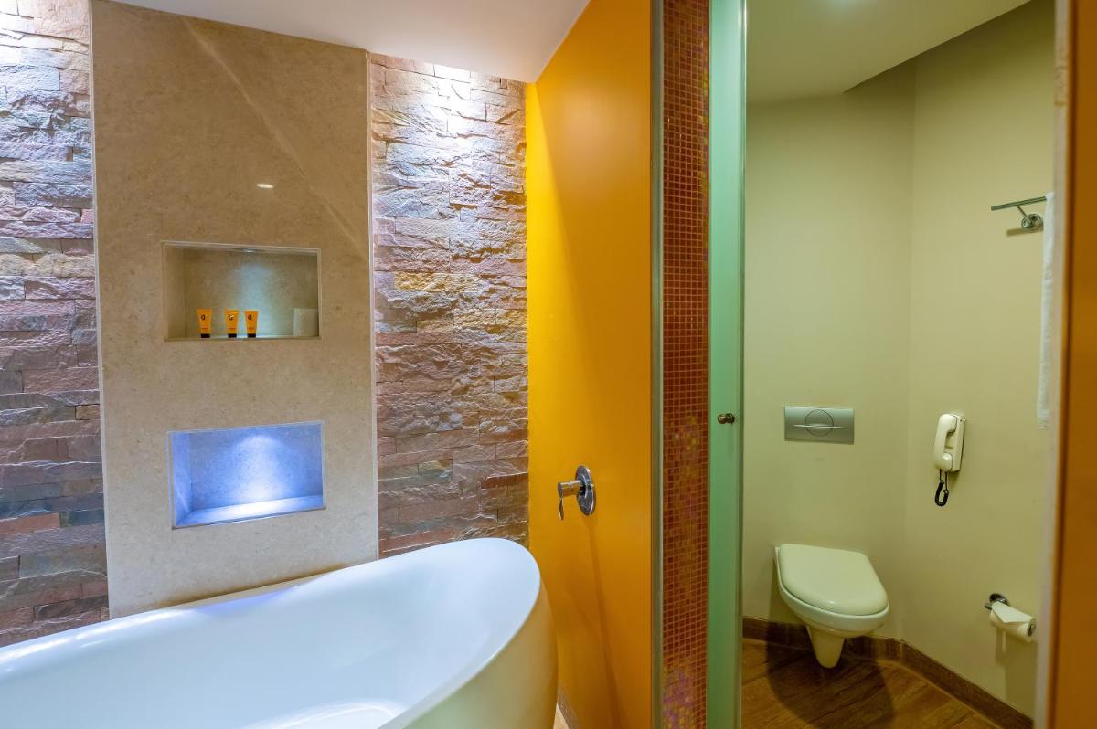 a bathroom with a tub and a toilet at O Hotel Pune in Pune