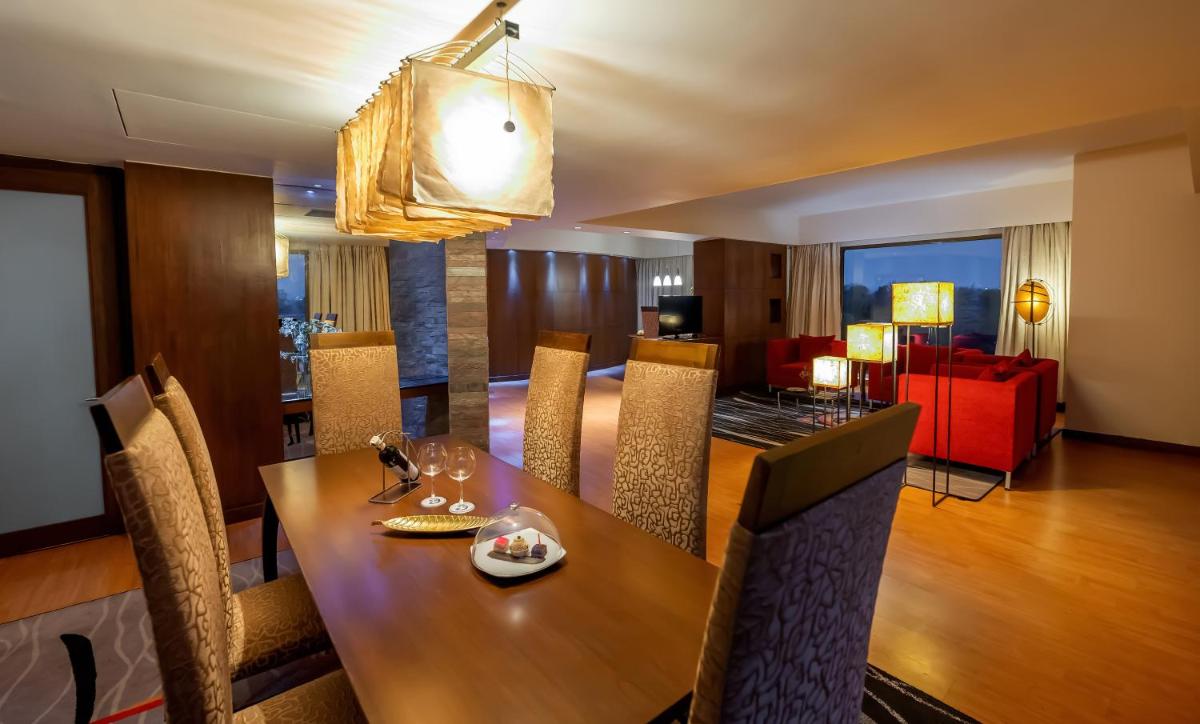 a dining room with a table and a red couch at O Hotel Pune in Pune