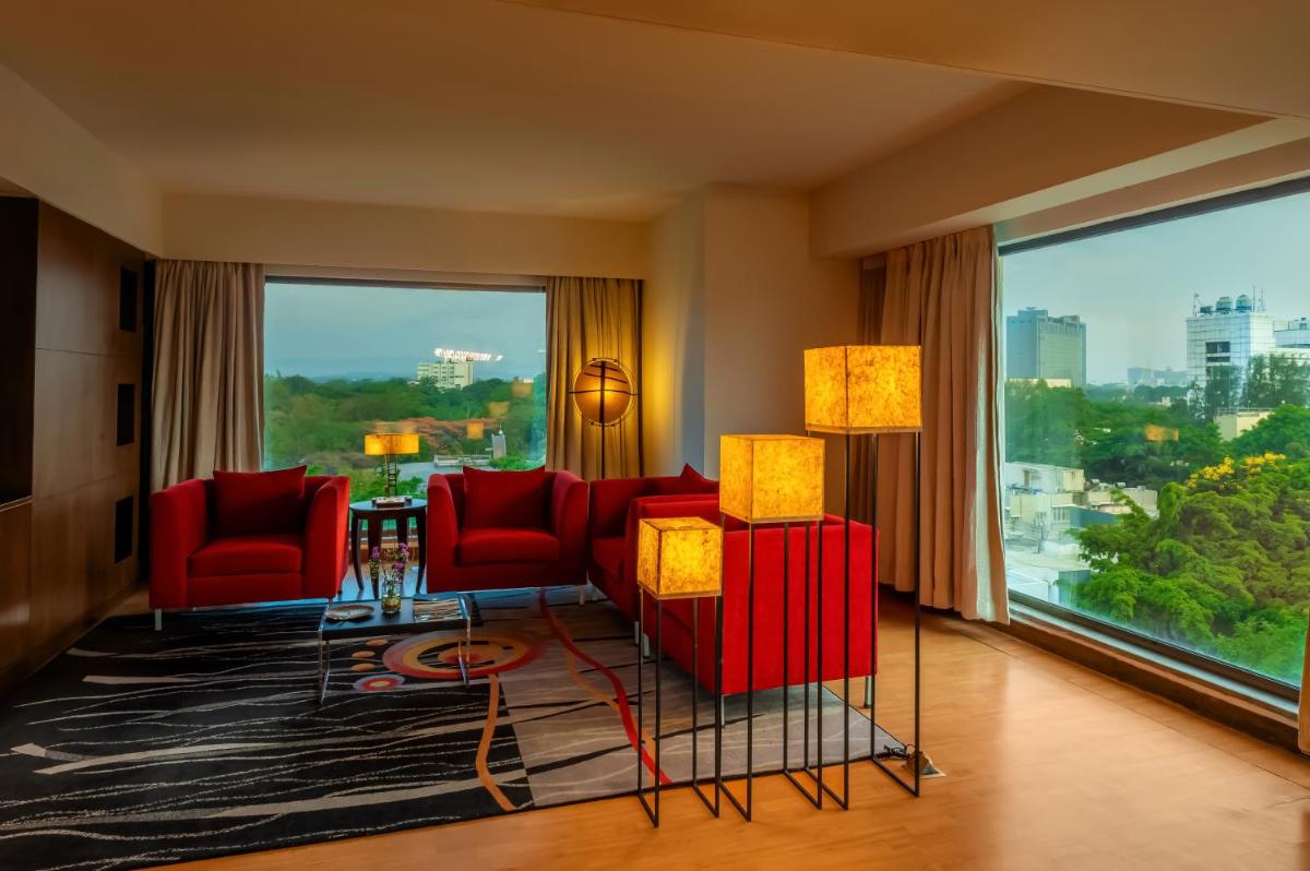 a living room with red chairs and a large window at O Hotel Pune in Pune