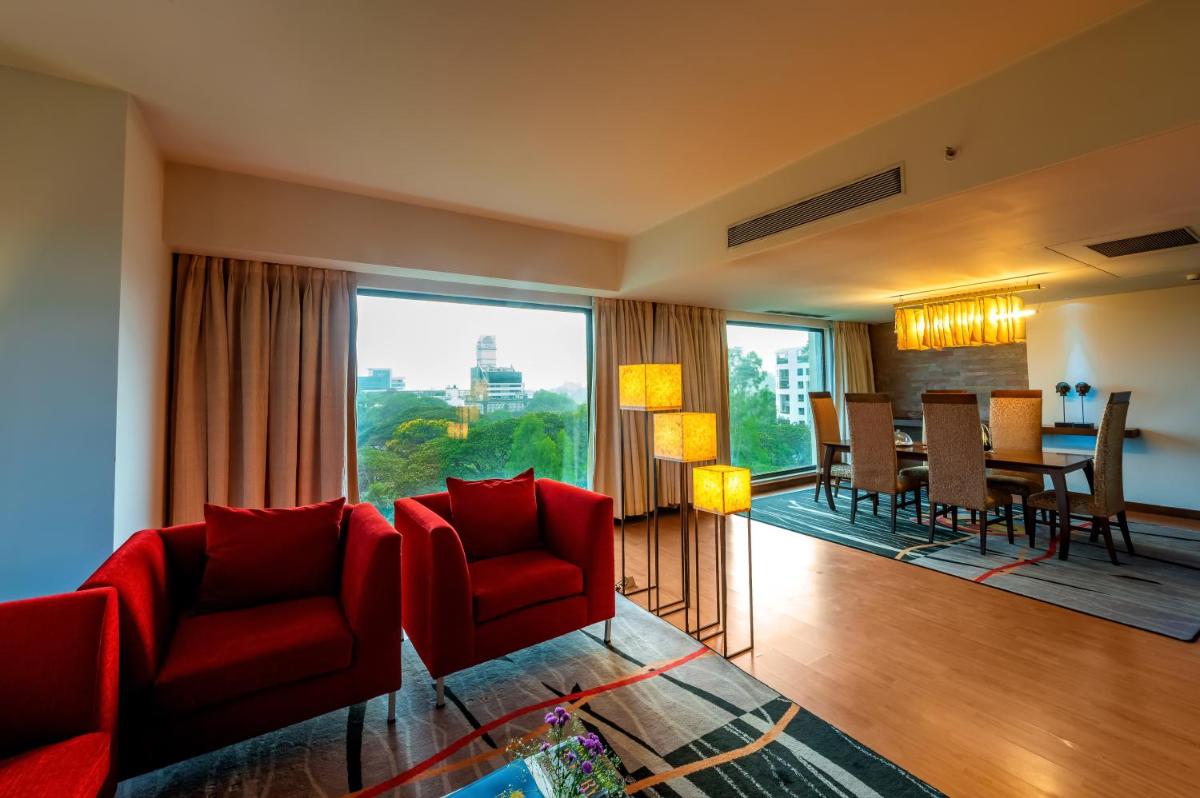 a living room with red chairs and a dining room at O Hotel Pune in Pune