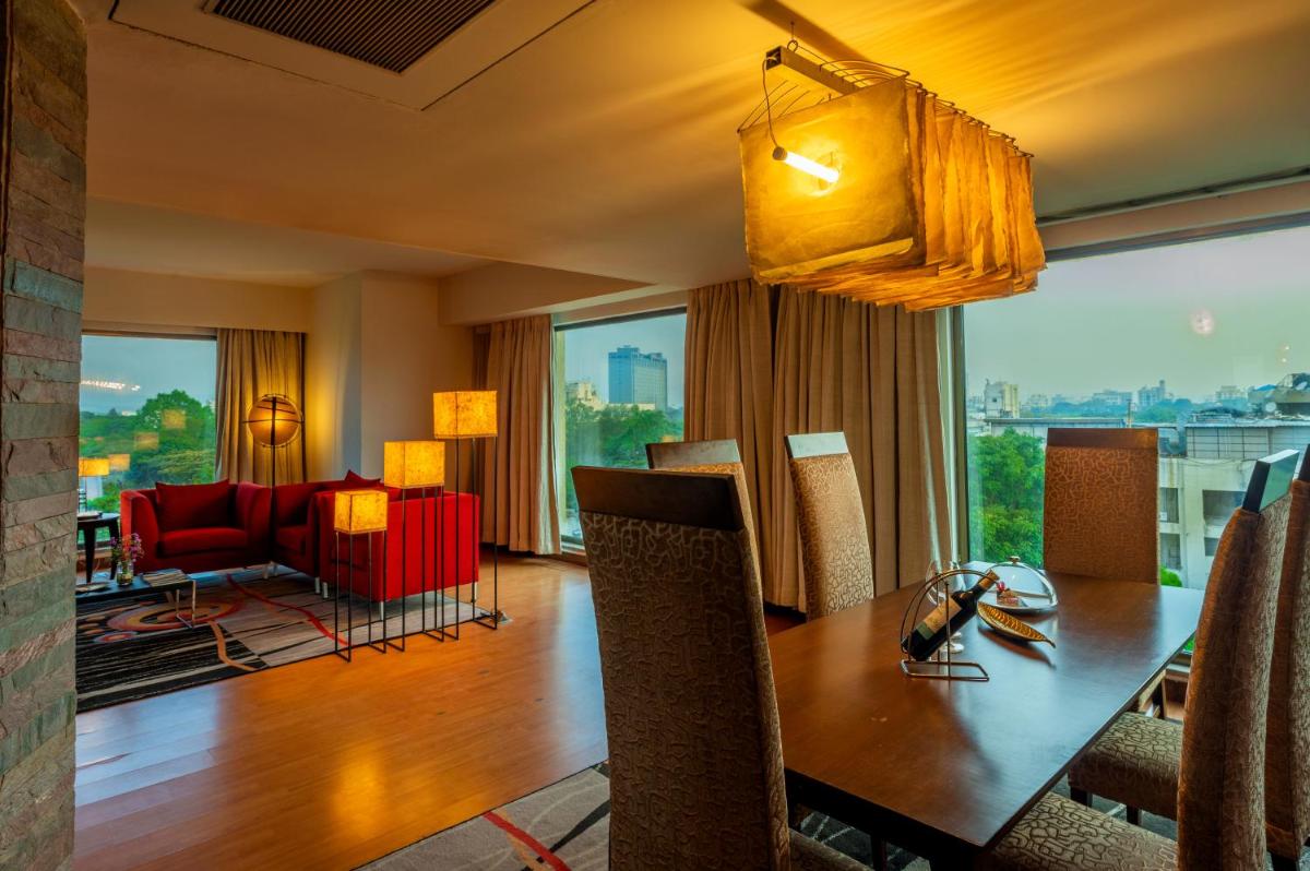a dining room with a table and a room with a view at O Hotel Pune in Pune