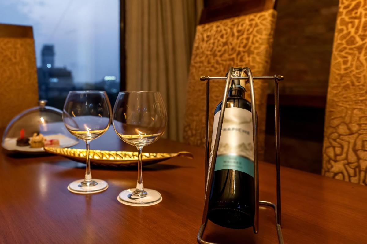 a bottle of wine and two glasses on a table at O Hotel Pune in Pune