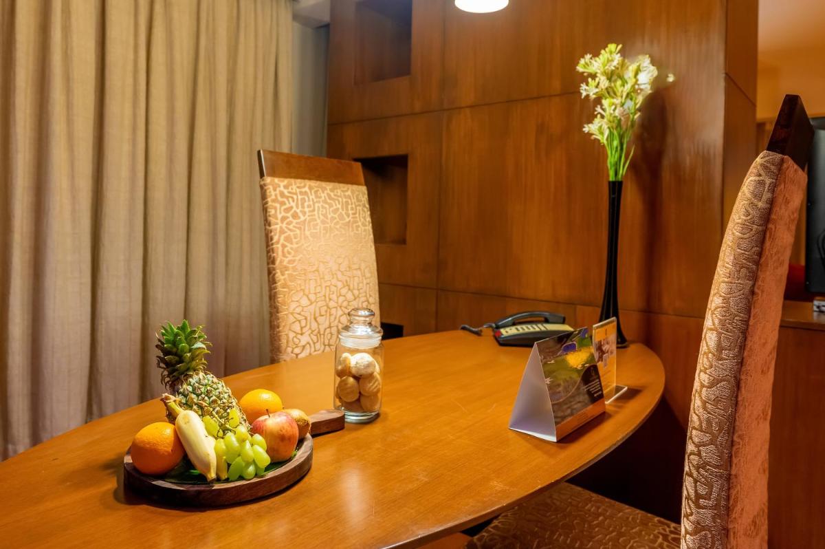 a wooden table with a bowl of fruit on it at O Hotel Pune in Pune