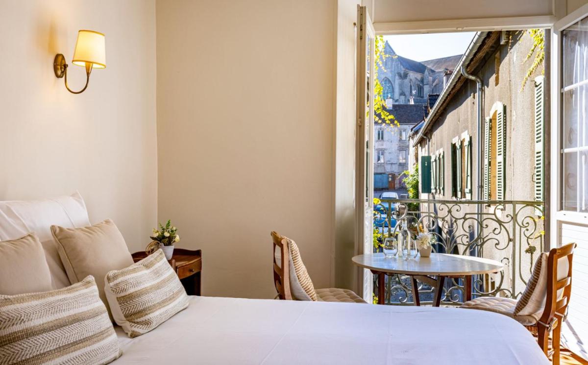 - une chambre avec un lit et une table sur un balcon dans l'établissement Logis Relais de la Source, à Saint-Seine-lʼAbbaye