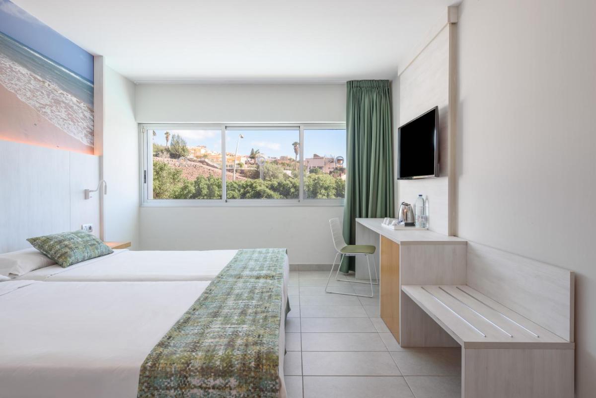 Una habitación de hotel con dos camas y una ventana. en FERGUS Cactus Garden, en Playa de Jandía