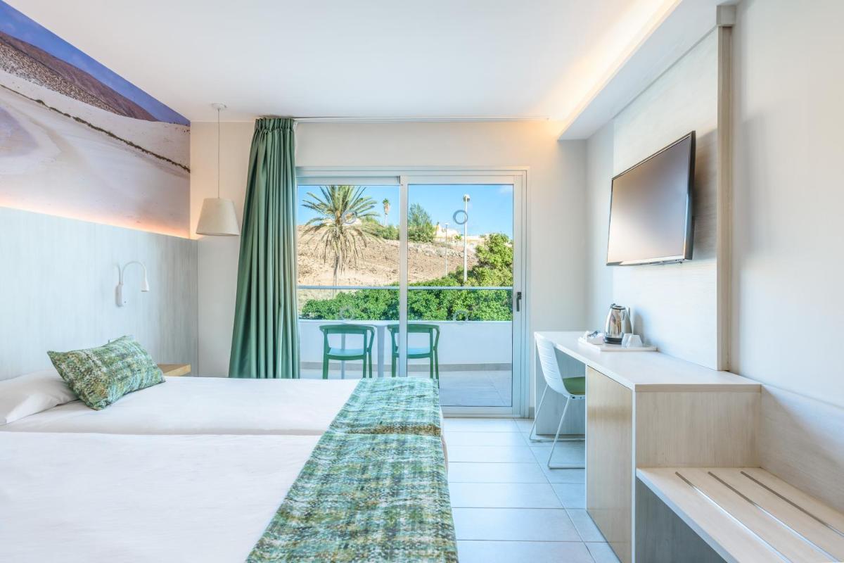 una habitación de hotel con una cama y un balcón en FERGUS Cactus Garden, en Playa de Jandía