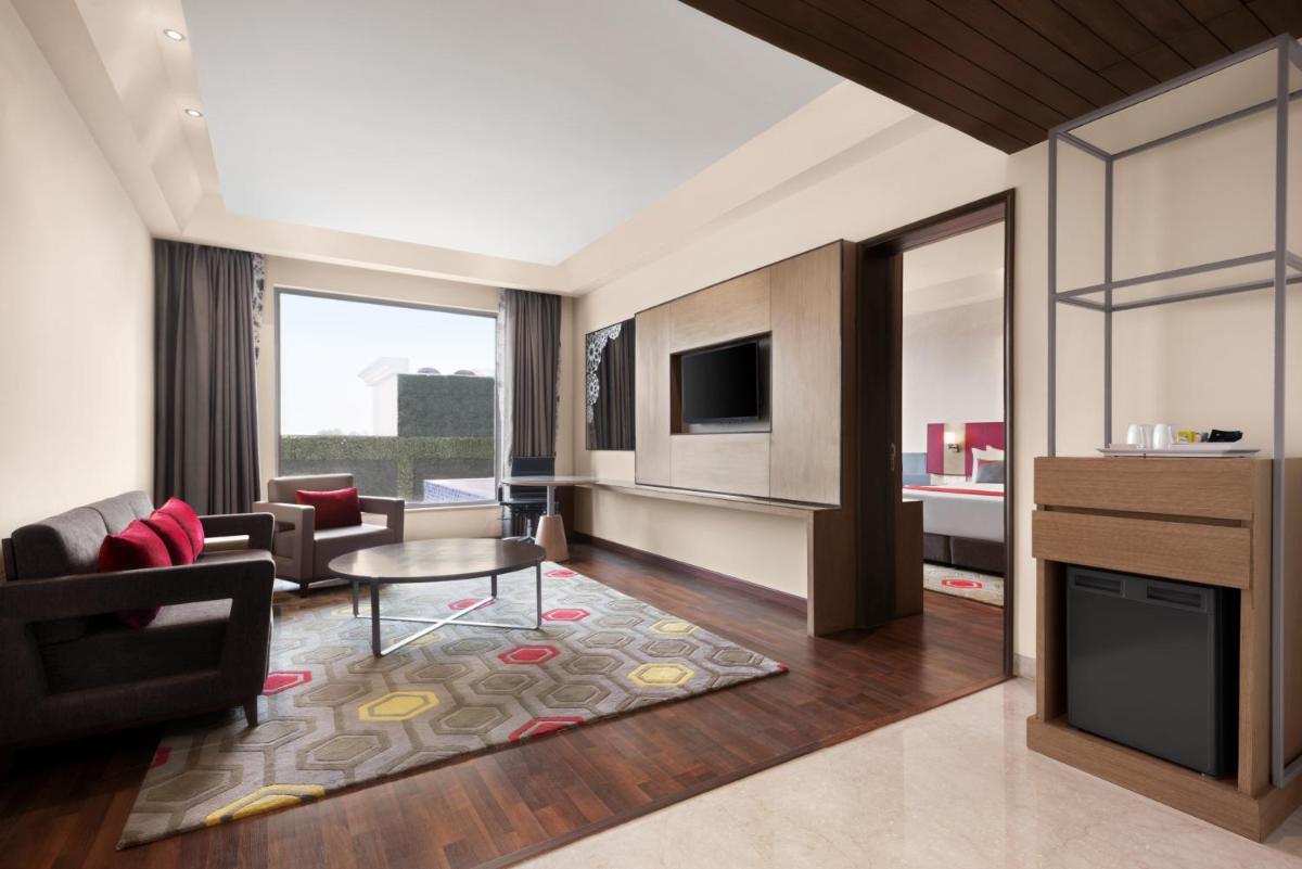 a living room with a couch and a table at Ramada by Wyndham Lucknow Hotel and Convention Center in Lucknow