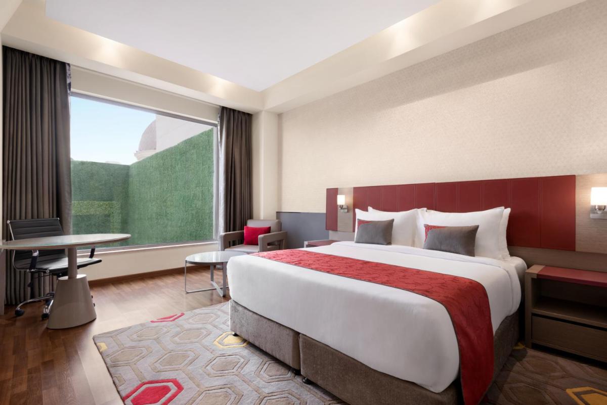 a hotel room with a large bed and a window at Ramada by Wyndham Lucknow Hotel and Convention Center in Lucknow