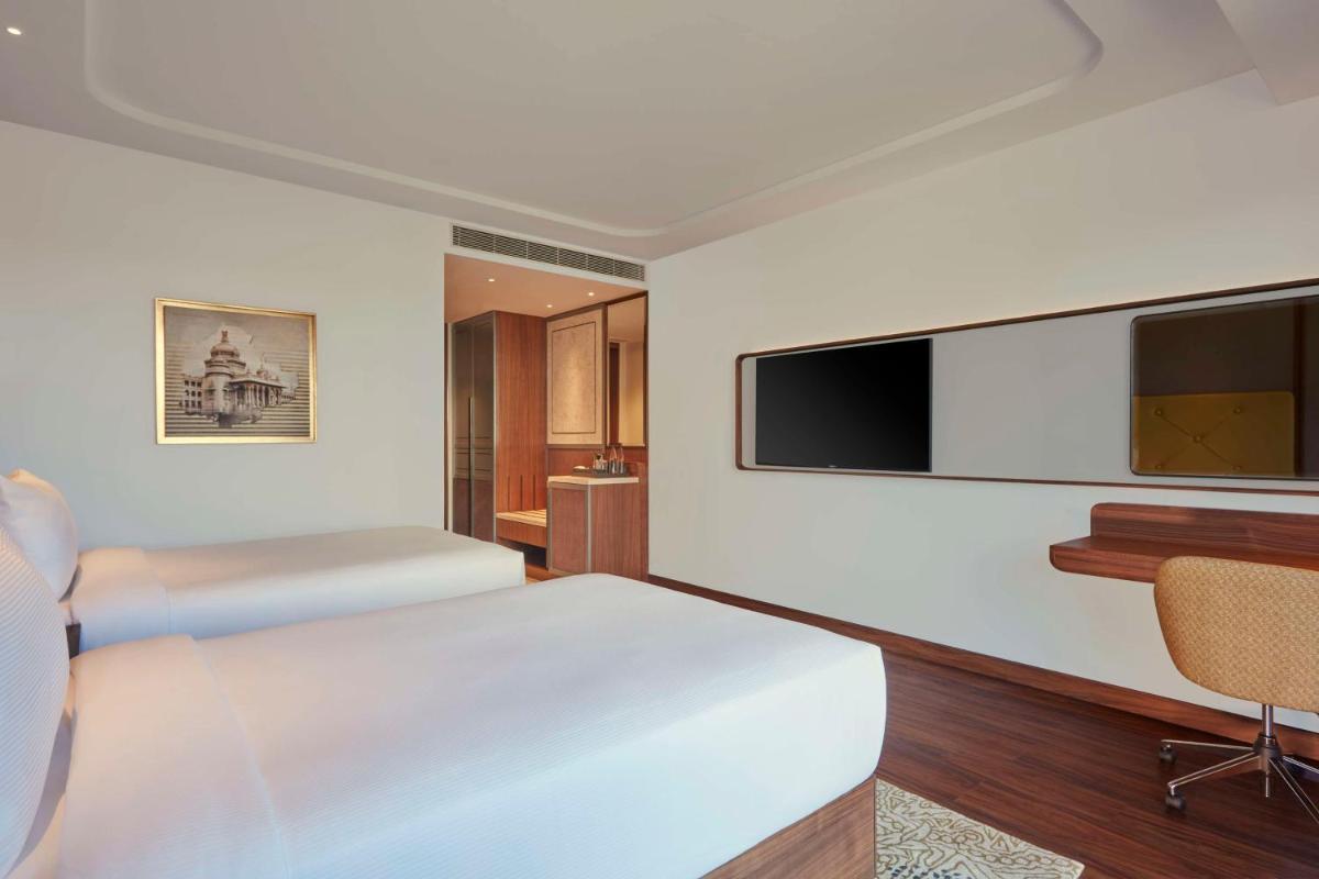 a hotel room with a bed and a flat screen tv at Doubletree By Hilton Bengaluru Whitefield in Bengaluru
