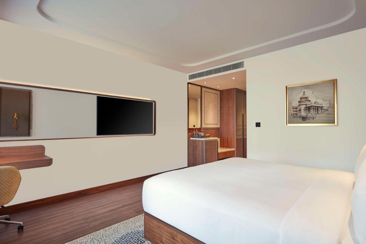 a bedroom with a white bed and a flat screen tv at Doubletree By Hilton Bengaluru Whitefield in Bengaluru