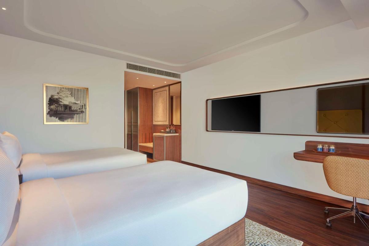 a hotel room with a bed and a flat screen tv at Doubletree By Hilton Bengaluru Whitefield in Bengaluru