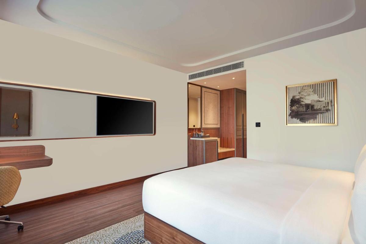 a bedroom with a white bed and a flat screen tv at Doubletree By Hilton Bengaluru Whitefield in Bengaluru