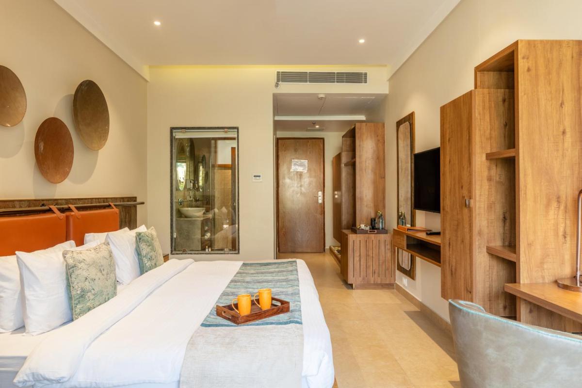 a hotel room with a bed and a television at Antalya By Divine Ganga Cottage in Rishīkesh