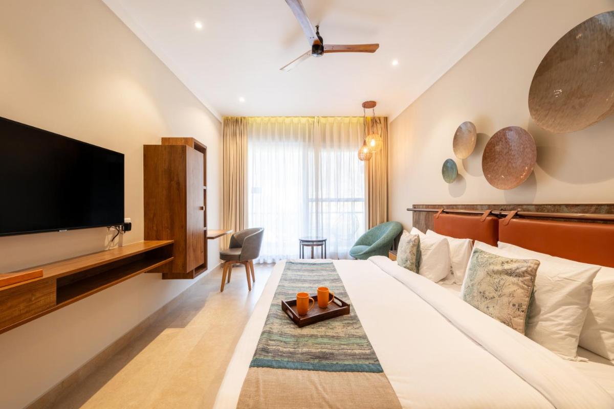 a hotel room with a bed and a flat screen tv at Antalya By Divine Ganga Cottage in Rishīkesh