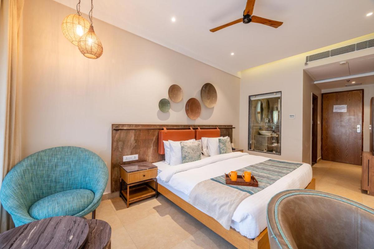 a bedroom with a bed and two chairs at Antalya By Divine Ganga Cottage in Rishīkesh