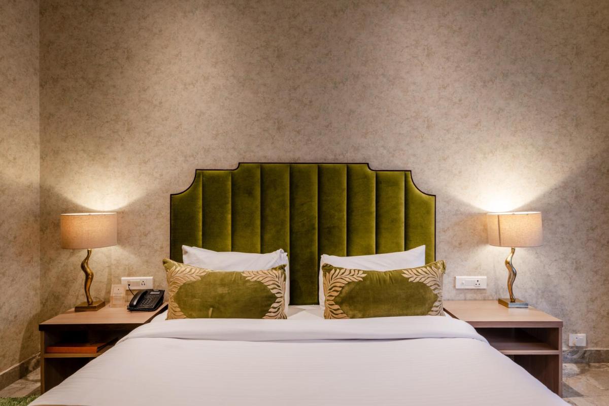 a bedroom with a large bed with a green headboard at Antalya By Divine Ganga Cottage in Rishīkesh