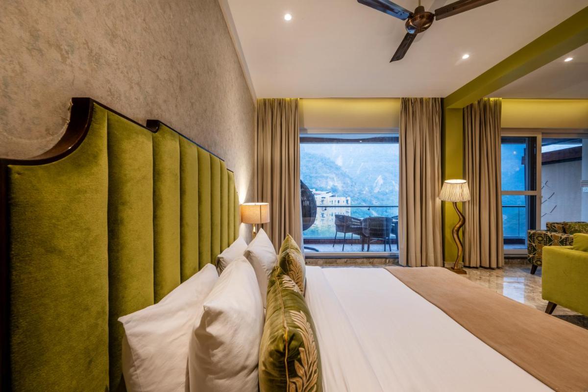 a bedroom with a large bed with a green headboard at Antalya By Divine Ganga Cottage in Rishīkesh