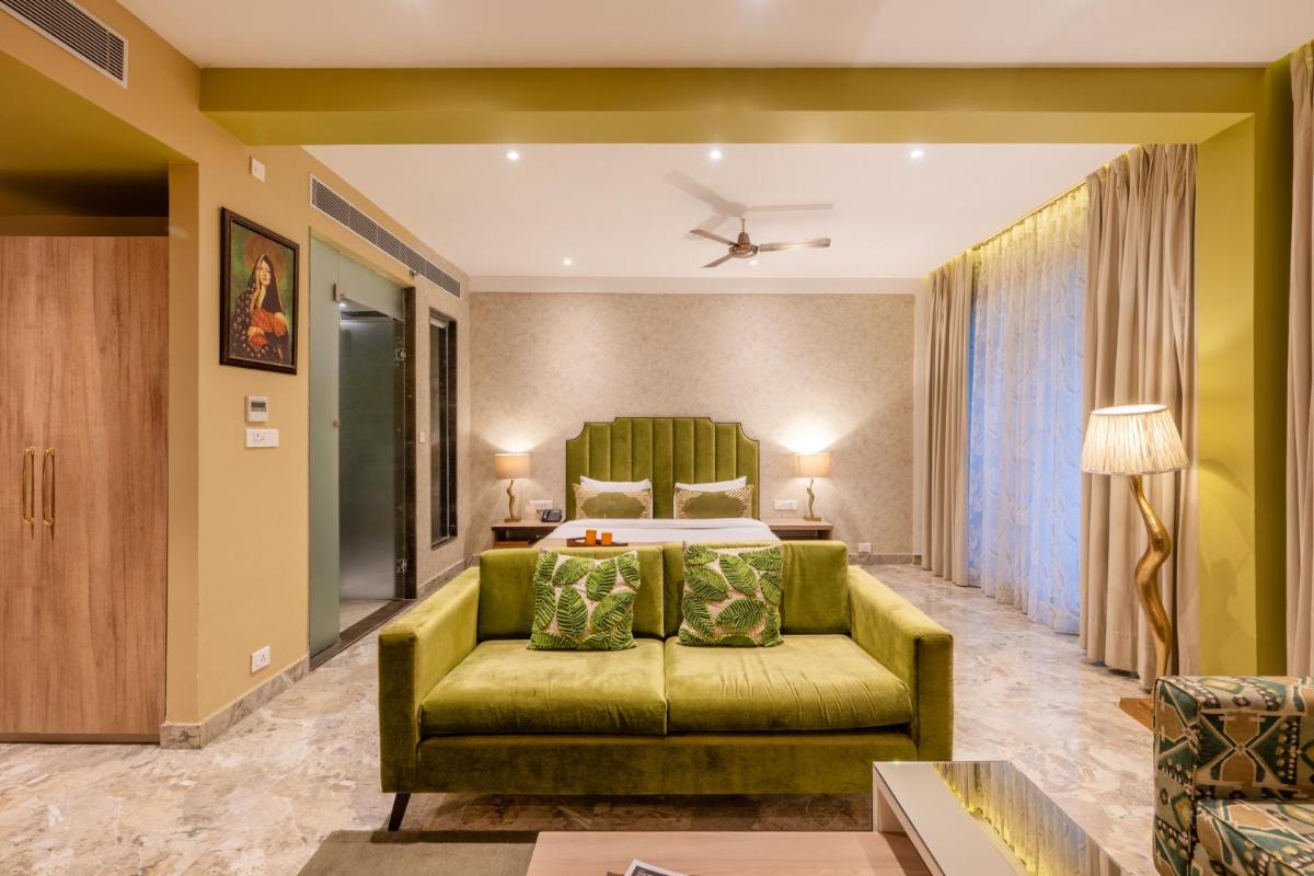 a living room with a green couch and a bed at Antalya By Divine Ganga Cottage in Rishīkesh