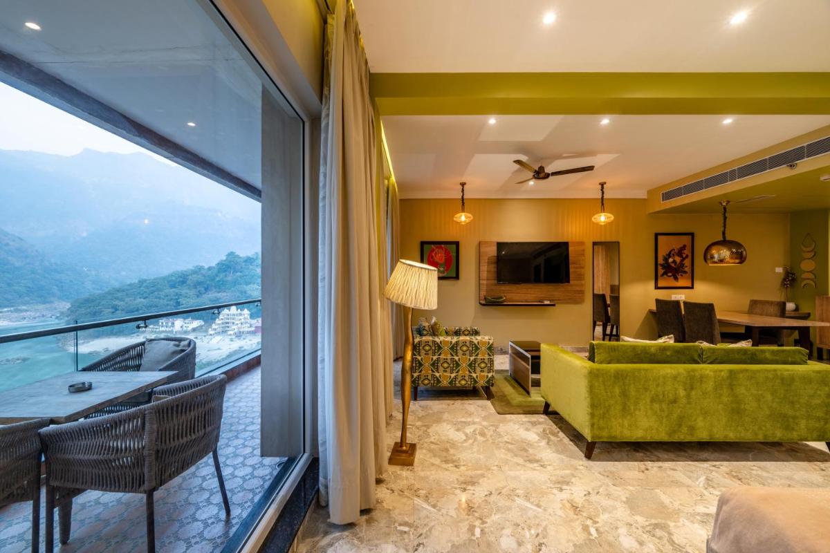 a living room with a green couch and a large window at Antalya By Divine Ganga Cottage in Rishīkesh