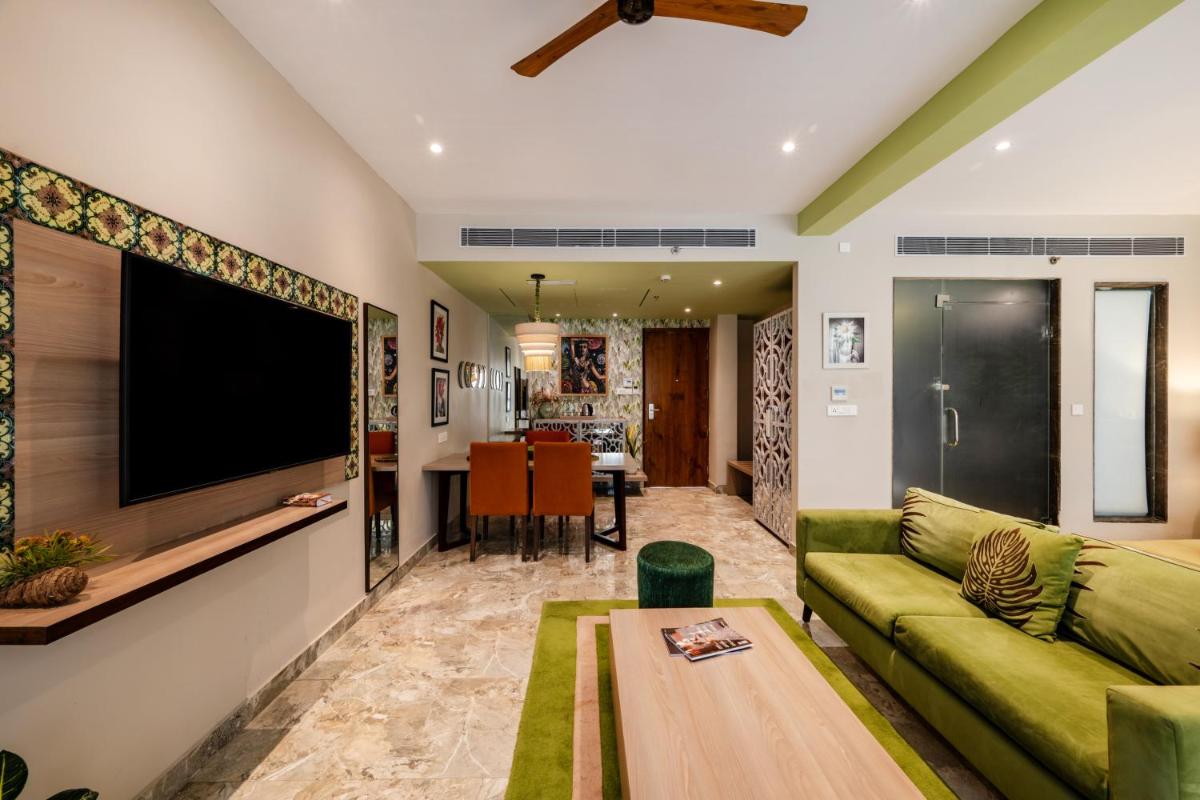 a living room with a green couch and a flat screen tv at Antalya By Divine Ganga Cottage in Rishīkesh