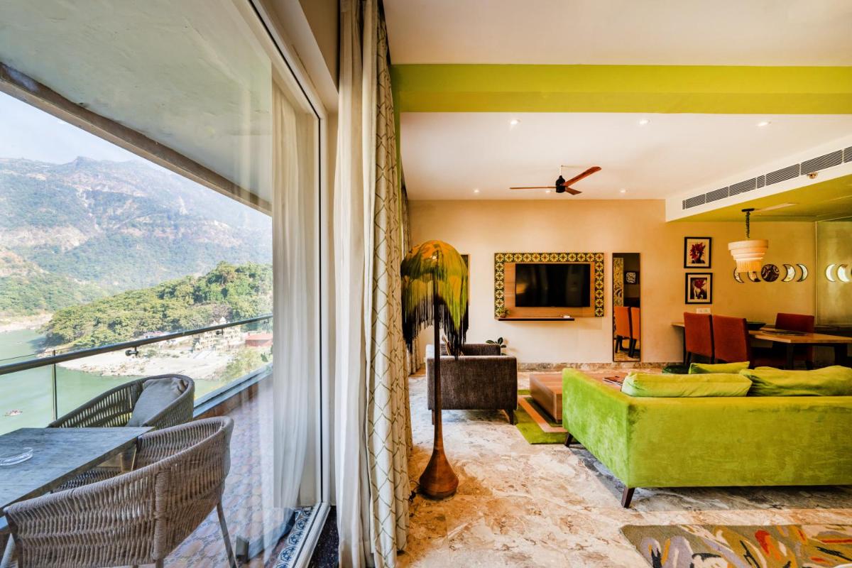 a living room with a green couch and a large window at Antalya By Divine Ganga Cottage in Rishīkesh