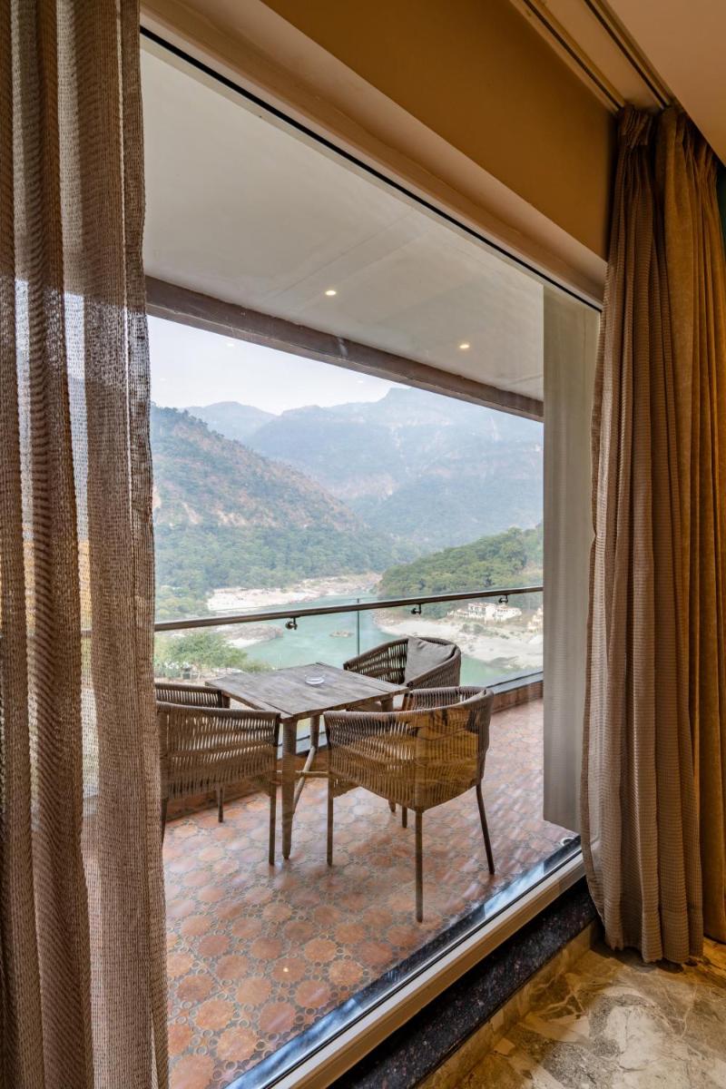 a balcony with a table and chairs and a large window at Antalya By Divine Ganga Cottage in Rishīkesh
