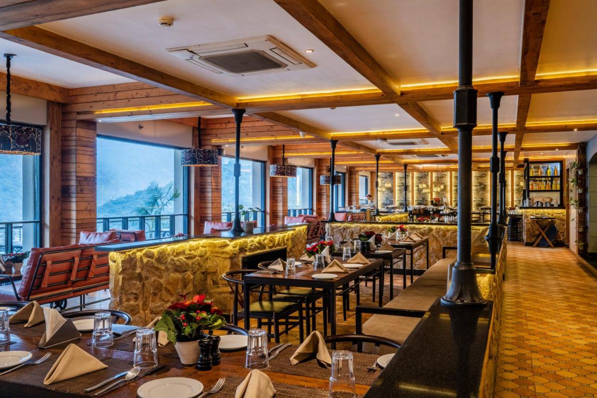 a restaurant with tables and chairs and large windows at Antalya By Divine Ganga Cottage in Rishīkesh
