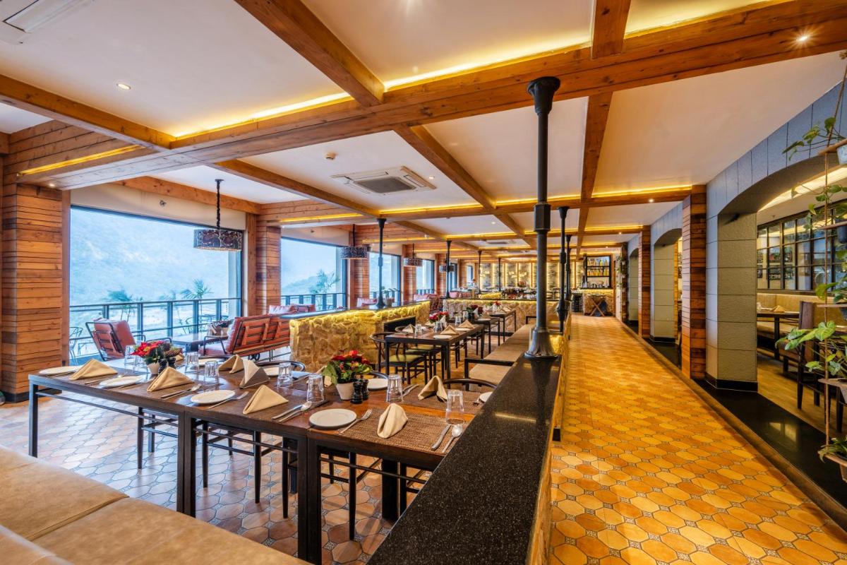 a restaurant with tables and chairs and large windows at Antalya By Divine Ganga Cottage in Rishīkesh