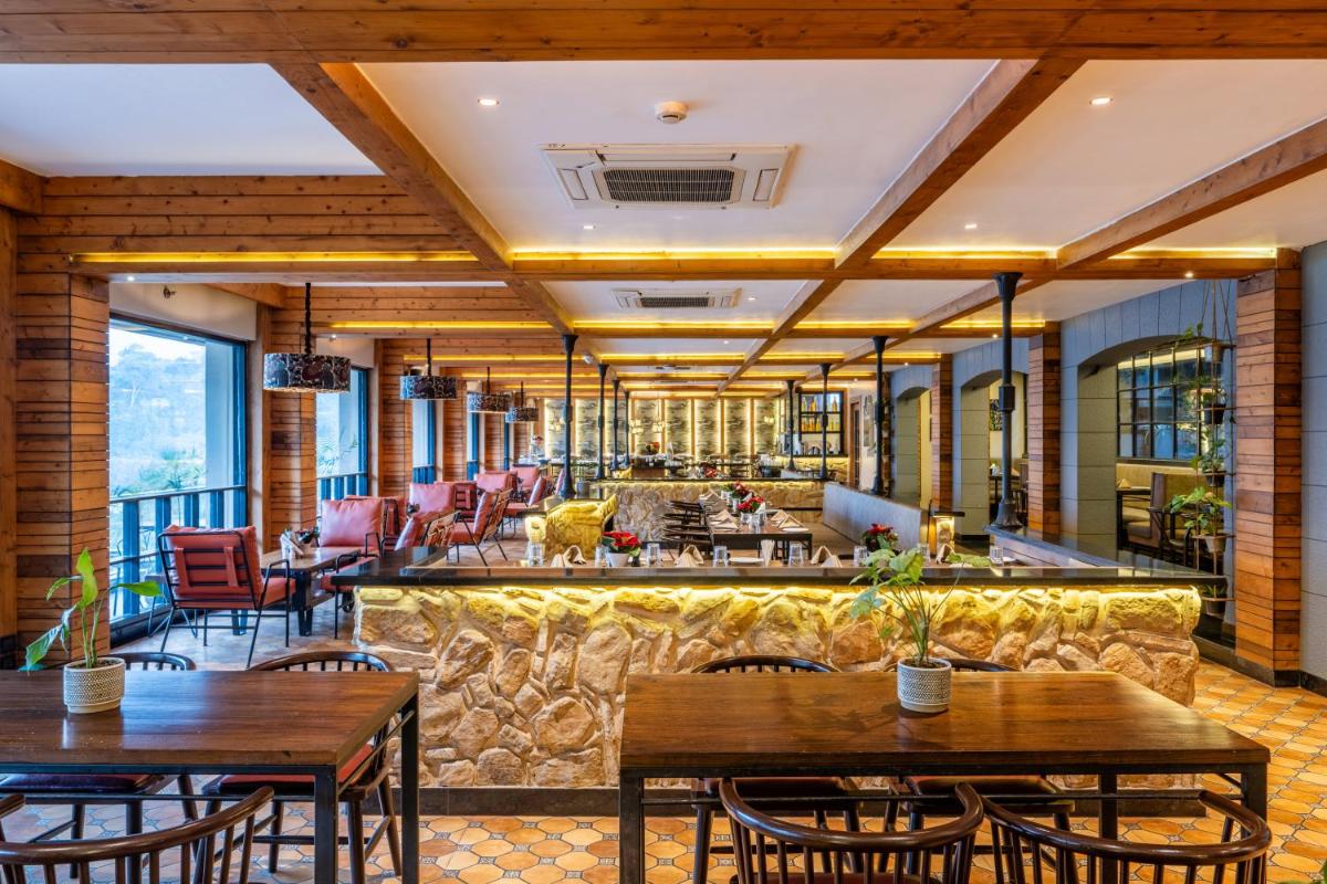 a restaurant with tables and chairs and a bar at Antalya By Divine Ganga Cottage in Rishīkesh