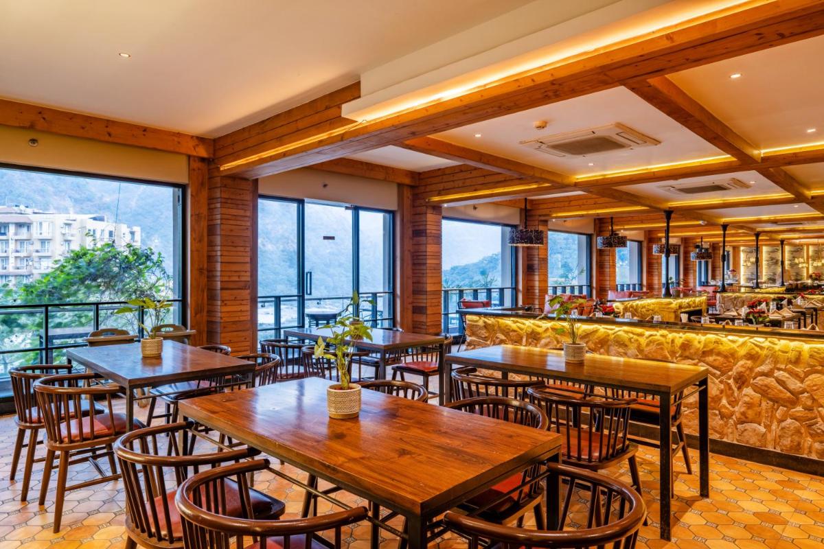a restaurant with tables and chairs and a bar at Antalya By Divine Ganga Cottage in Rishīkesh