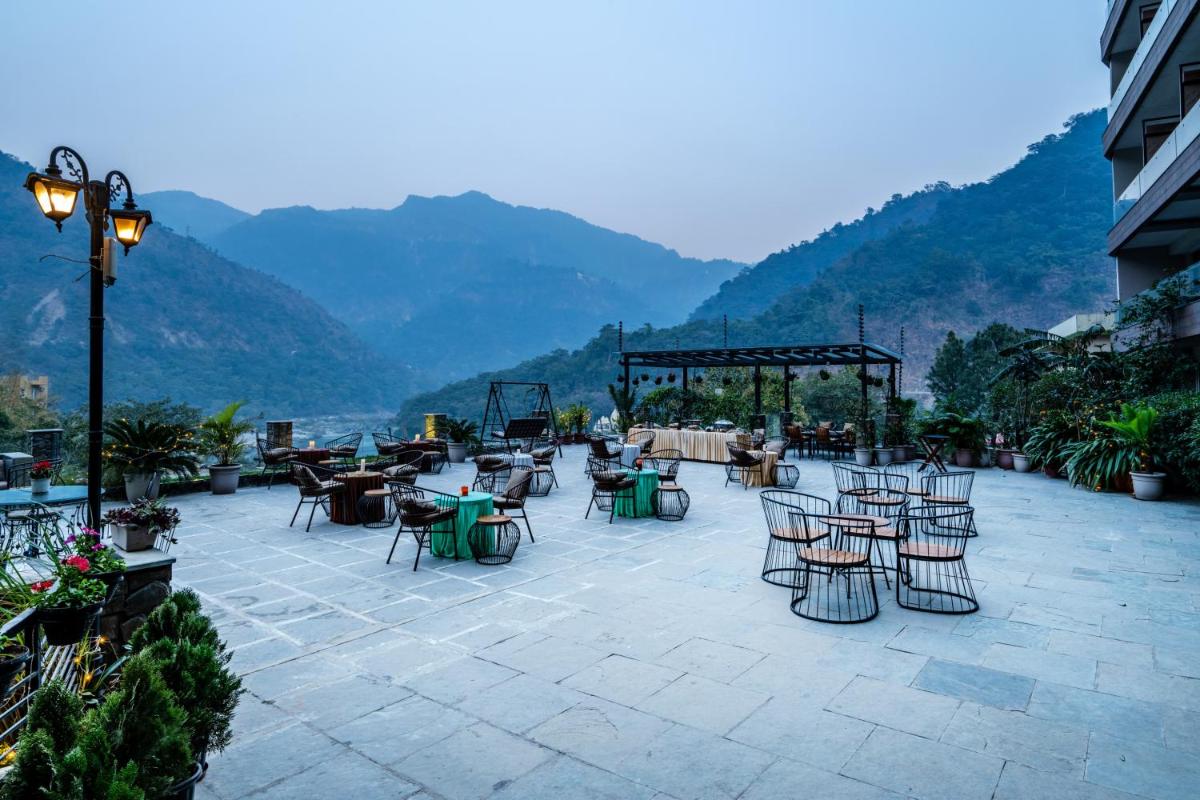 a patio with tables and chairs with mountains in the background at Antalya By Divine Ganga Cottage in Rishīkesh