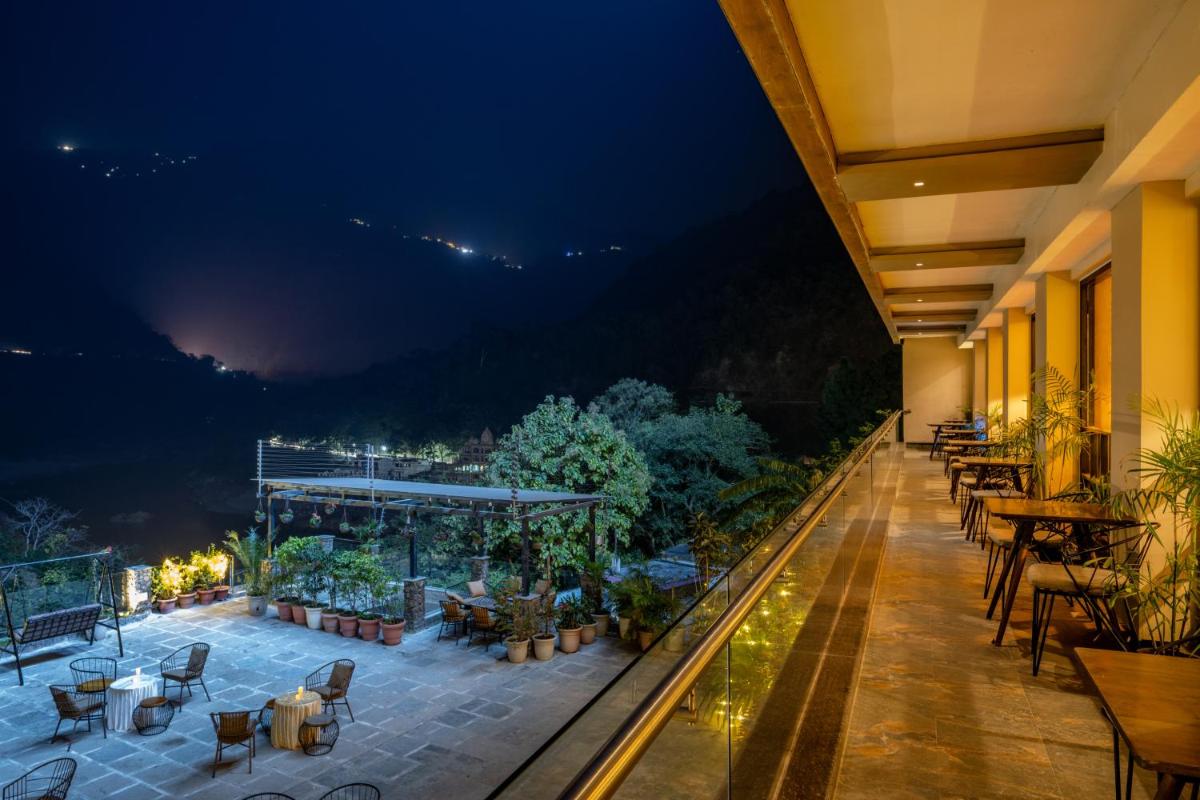 a hotel balcony with tables and chairs at night at Antalya By Divine Ganga Cottage in Rishīkesh