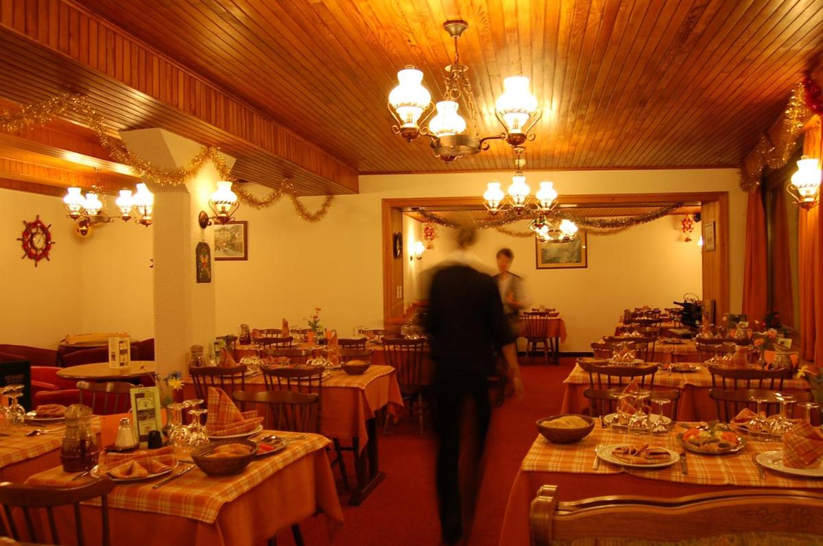 Un homme se promenant dans une pièce pleine de tables dans l'établissement Hôtel Les Côtes, Résidence Loisirs et Chalets, à Morzine 96 autres photos