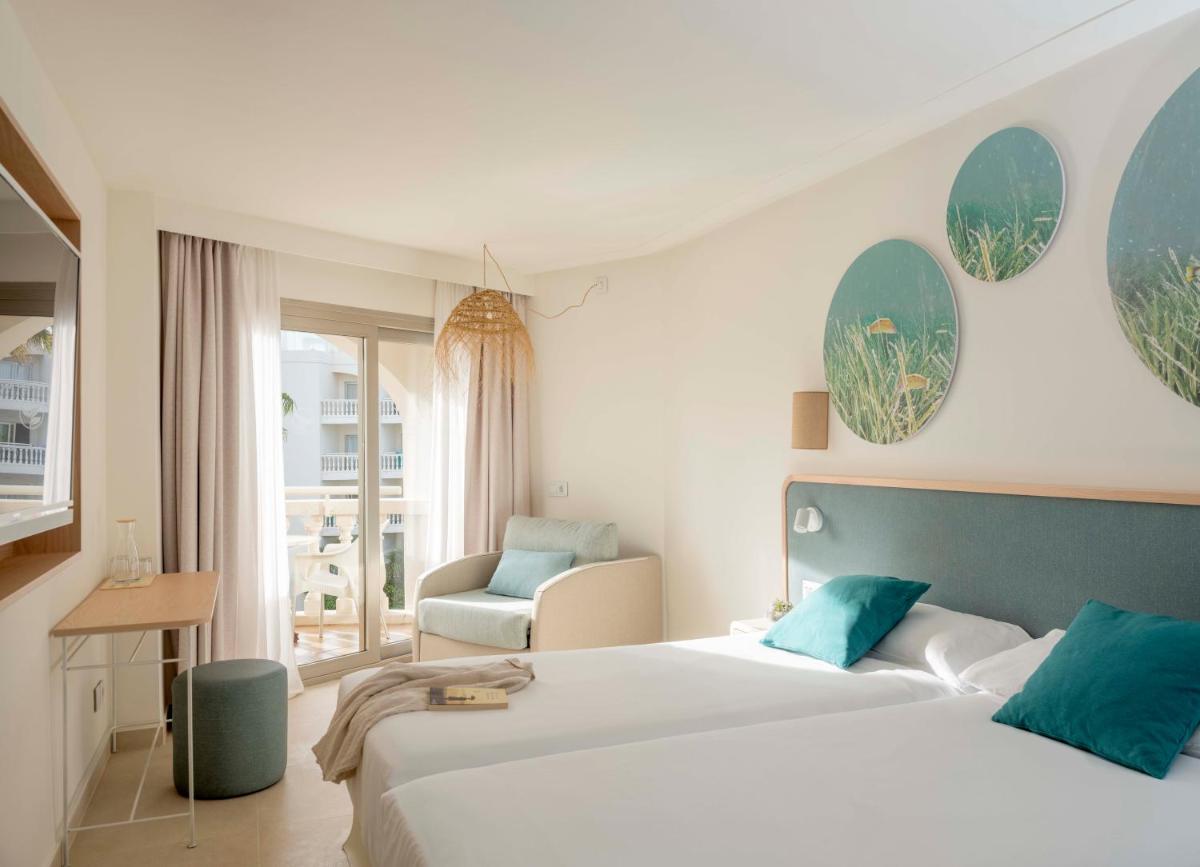 una habitación de hotel con dos camas y una silla en Iberostar Selection Albufera Playa All Inclusive, en Playa de Muro